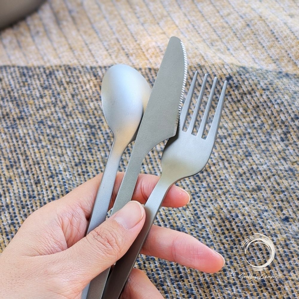 Titanium knife, fork and spoon set held in hand outdoors