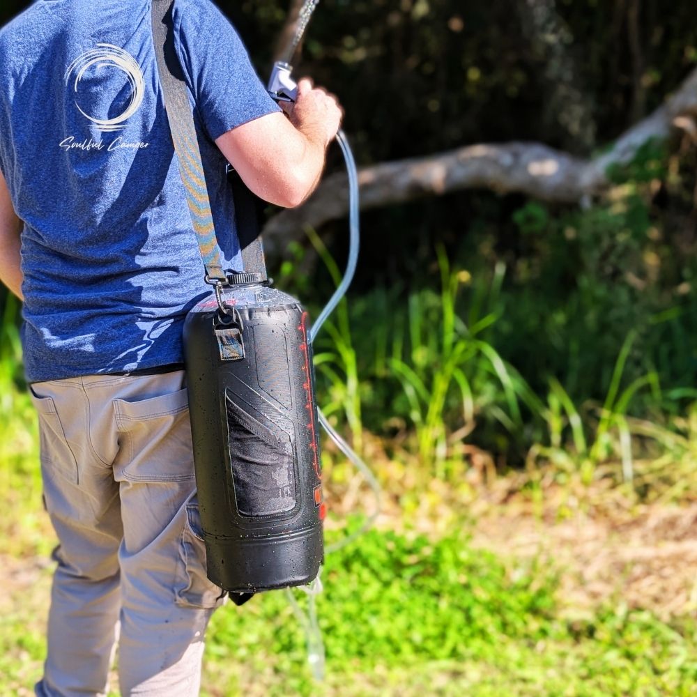 Man carrying Soulful Camper Sun Shower on shoulder during outdoor adventure