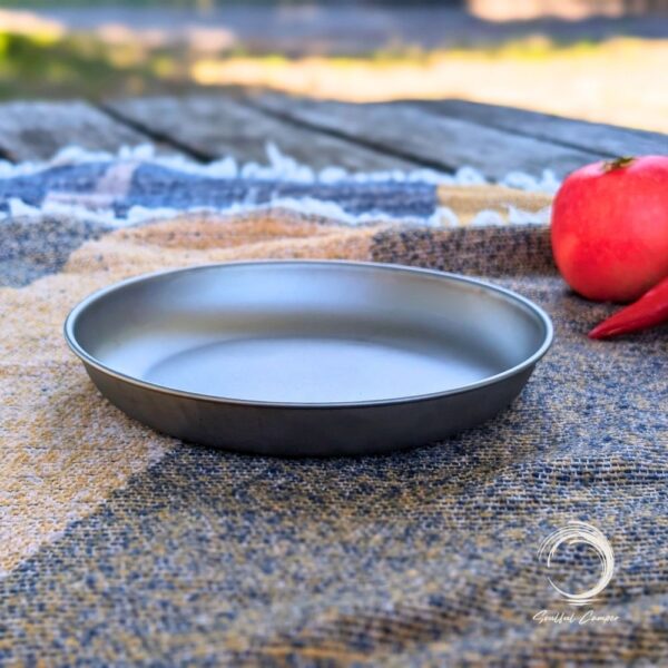 Side profile of titanium camping plate on woven picnic blanket
