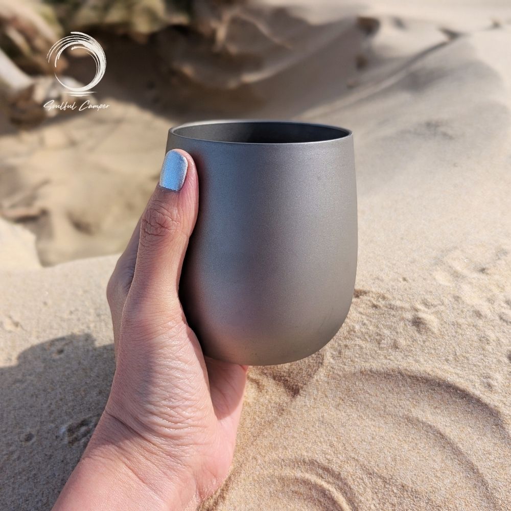 Close-up of titanium cup held in hand, showcasing ergonomic size and sleek finish.