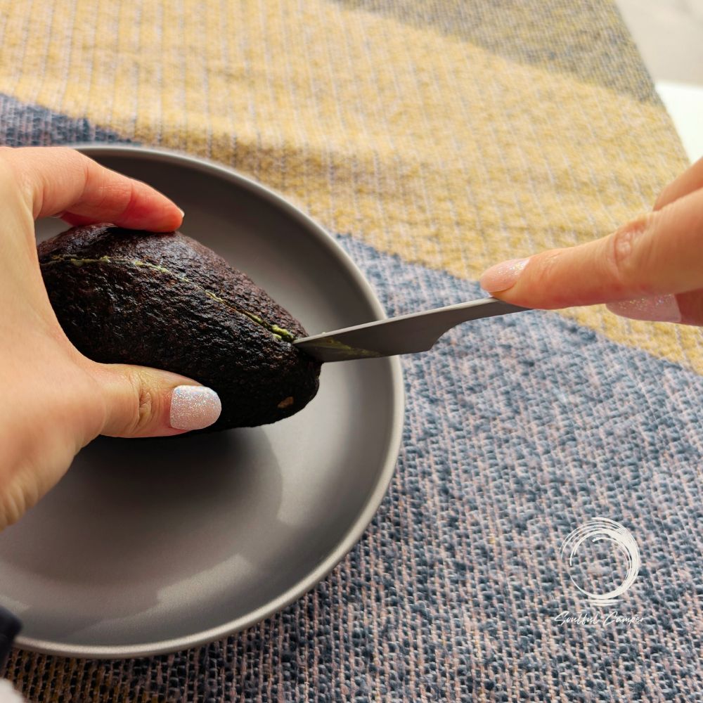 Titanium camping knife slicing a fresh avocado on a Ti-plate
