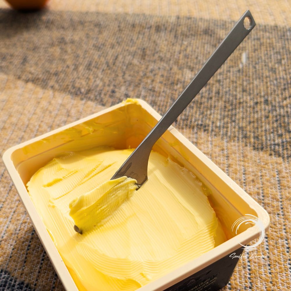 Titanium butter knife spreading margarine on a warm breakfast table
